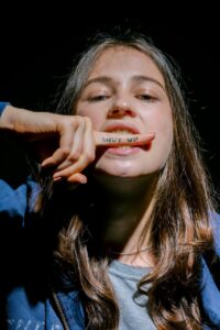 a young woman with shut up note on index finger